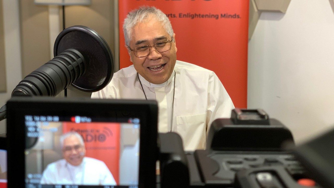 Cardinal William Goh talking in front of cameras